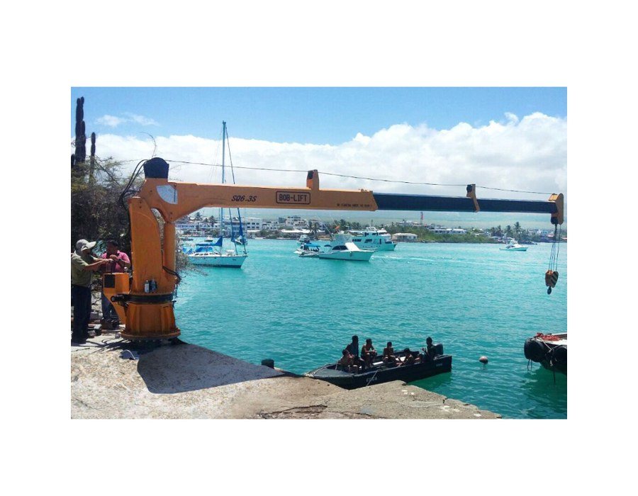 Orange BOB-LIFT 6.3 t Grues marines à flèche télescopique installed on a quayside with its boom extended over a harbor full of small boats